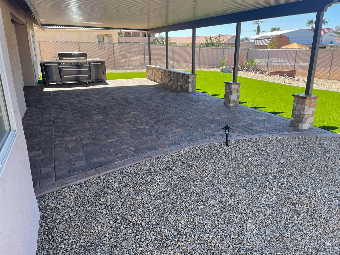 Covered patio with pavers and turf outdoor living space